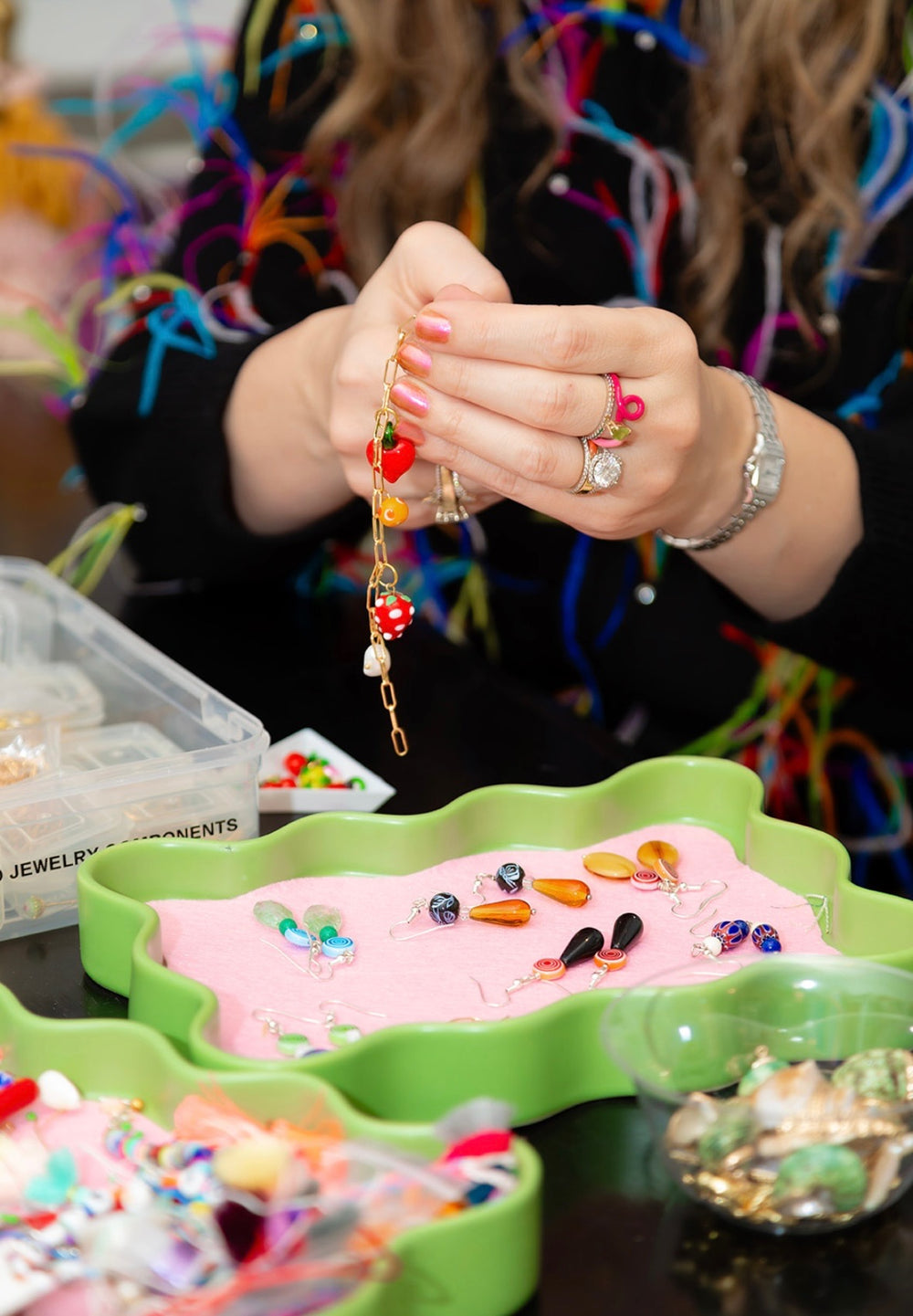Hands holding a finished beaded piece at the House of Perna worktable
