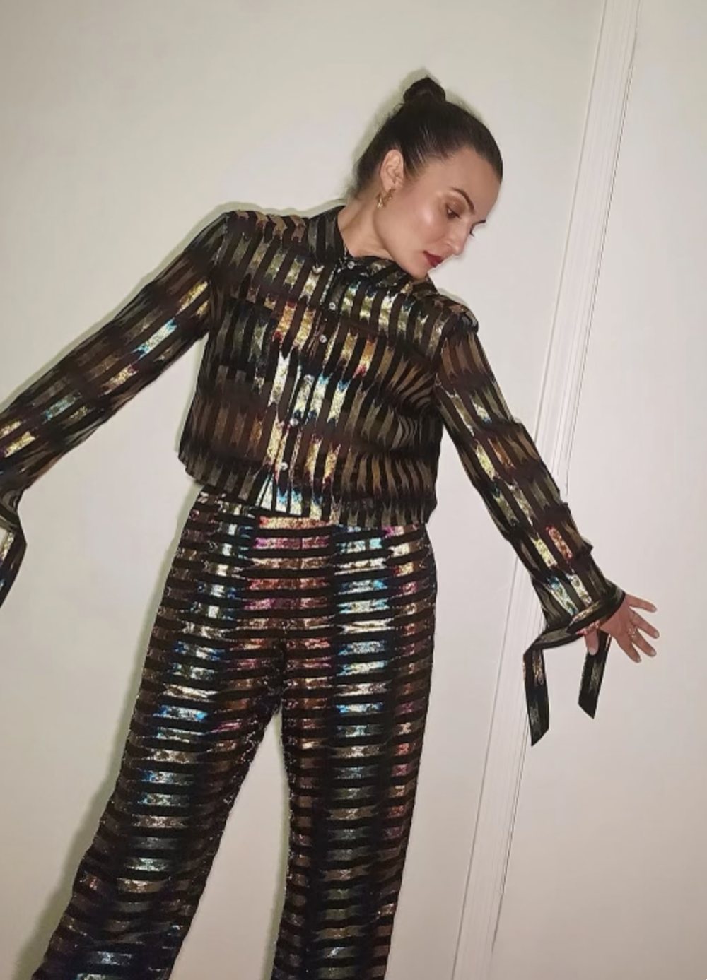 A woman in a metallic striped shirt and wide leg pants set