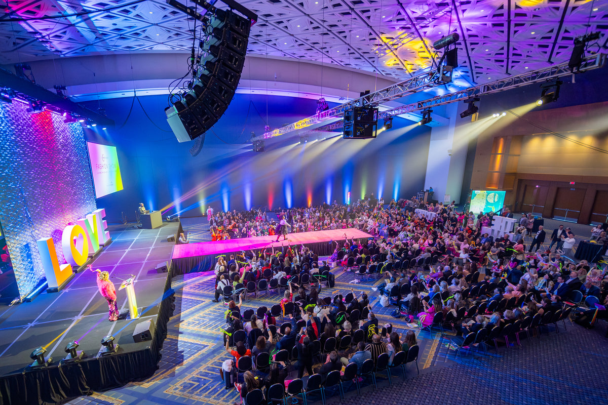 A large conference audience watching a fashion show runway